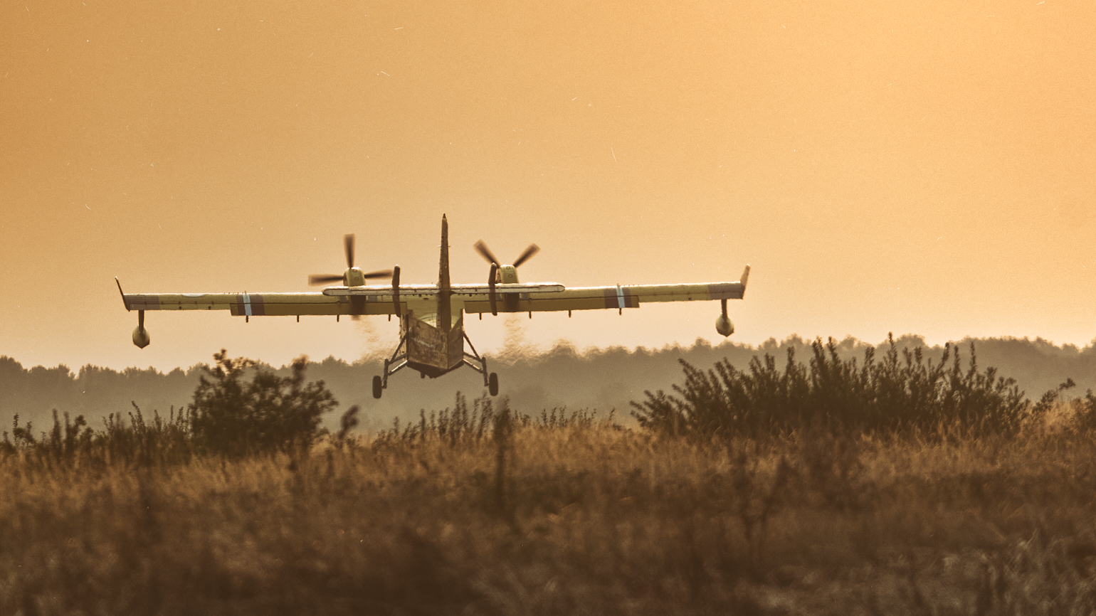 Canadair au décollage , vu du bout de piste, au coucher du soleil, avec arbres et brume au loin. fumées des incendies de gironde 2026
